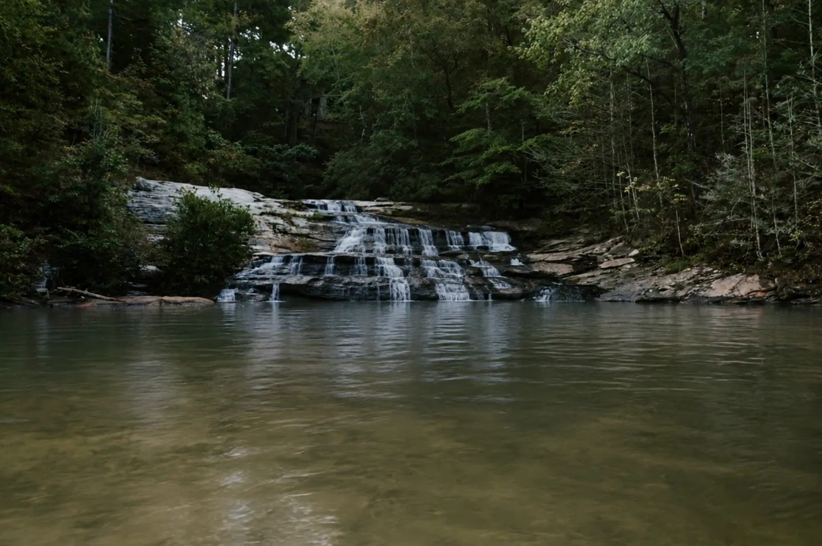 Waterfall spilling into the clear green water of Lake Keowee, Upstate South Carolina