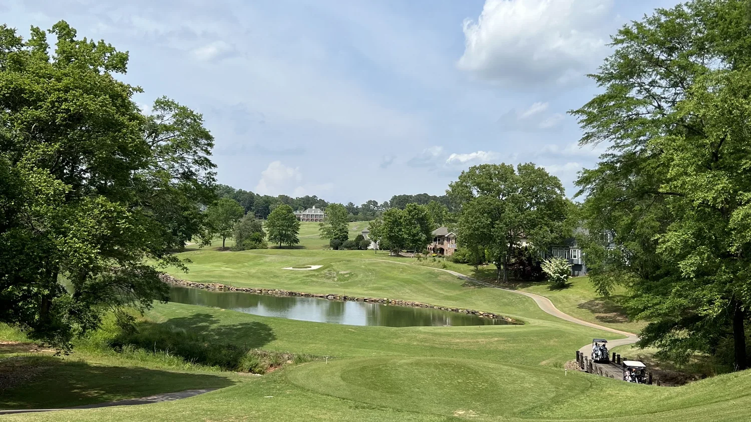 Fairway, pond and clubhouse at Cross Creek Plantation, a gated golf community in Seneca, South Carolina, with homes along the treeline